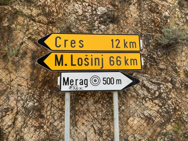 Wegweiser nach Cres (12 km), M. Lošinj (66 km) und Merag (500 m) in Kroatien.