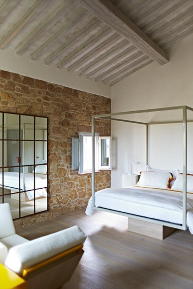 Ein Schlafzimmer mit einem Himmelbett und einer Wand aus Naturstein.