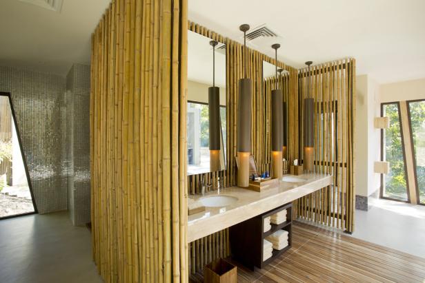 Ein Badezimmer mit Bambuswänden, mehreren Waschbecken und modernen Lampen.