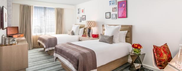 Ein Hotelzimmer mit zwei Betten, einem Plattenspieler und dekorativen Bildern an der Wand.