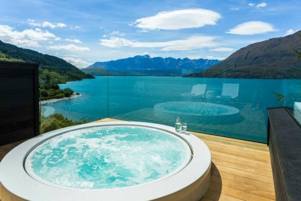 Ein Whirlpool auf einer Terrasse mit Blick auf einen See und Berge.