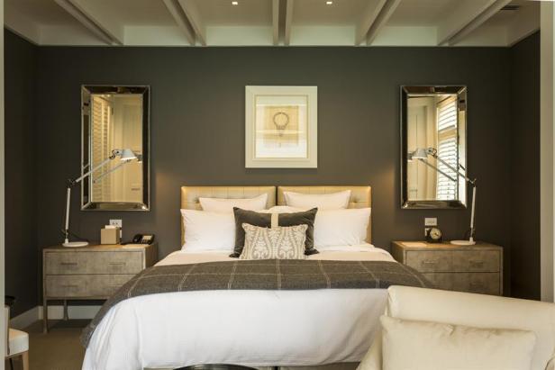 Ein Schlafzimmer mit einem Doppelbett, Nachttischen und Spiegeln.