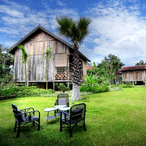 Ein Holzhaus auf Stelzen mit einer Sitzgruppe im Garten.