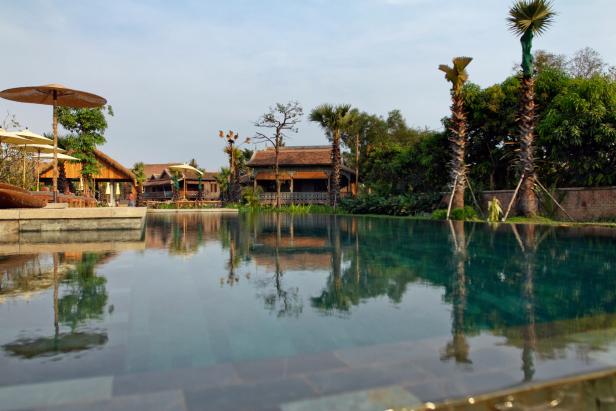 Ein ruhiger Pool spiegelt die umliegenden Gebäude und Palmen wider.