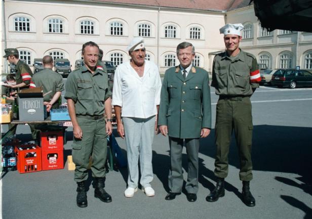 Eine Gruppe von Männern in Uniformen und Zivilkleidung steht zusammen.