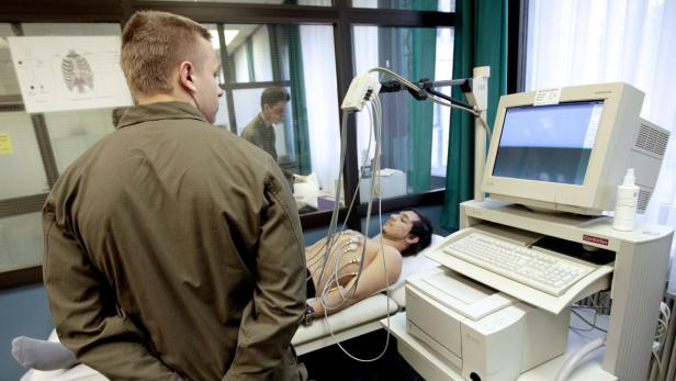 Ein Mann wird in einem Krankenhauszimmer an ein EKG-Gerät angeschlossen.