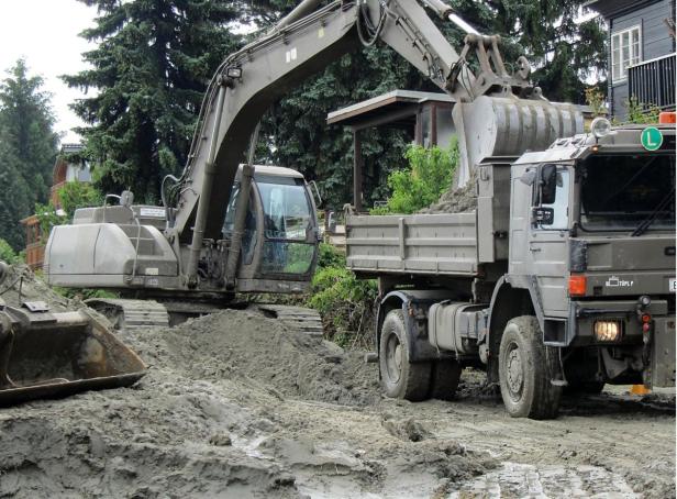 Ein Bagger belädt einen Lastwagen mit Erde.