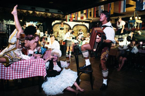 Feiernde Menschen in Tracht in einem bayerischen Lokal mit Live-Musik und Bier.