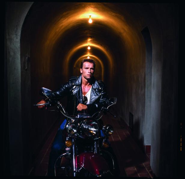 Arnold Schwarzenegger sitzt auf einem Motorrad in einem Tunnel.