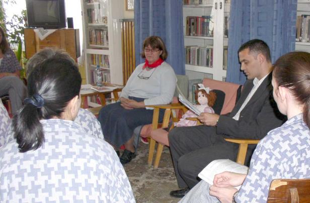 Eine Gruppe von Menschen sitzt in einem Raum und liest Bücher vor.