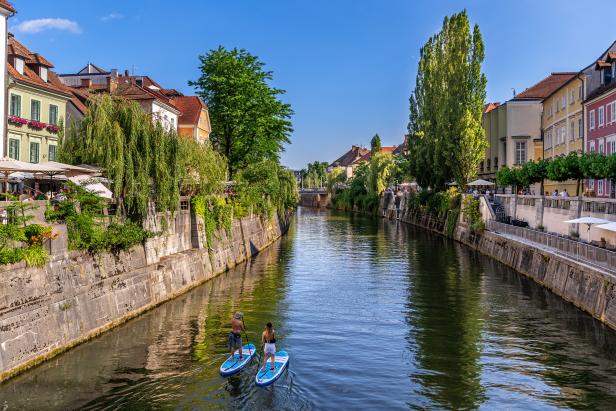 Zwei Personen paddeln auf Stand-Up-Paddleboards auf dem Fluss Ljubljanica.