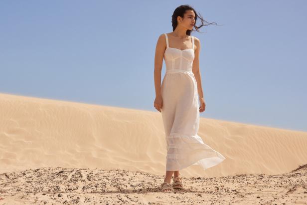 Eine Frau in einem weißen Kleid steht in einer Wüste.