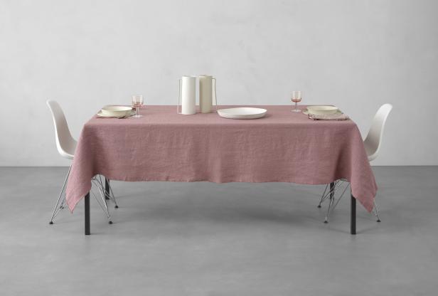 Ein gedeckter Tisch mit rosa Tischdecke, Geschirr und zwei weißen Vasen.