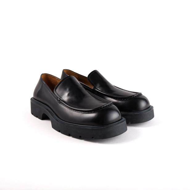 Ein Paar schwarze Loafer mit dicker Sohle stehen auf einem weißen Hintergrund.