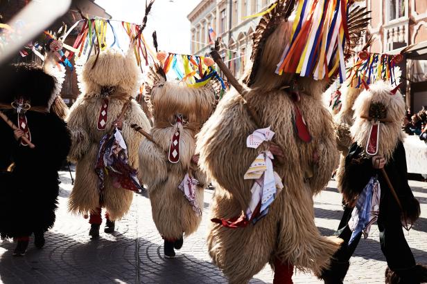Eine Gruppe von Kurenti-Figuren nimmt an einem Karnevalsumzug teil.