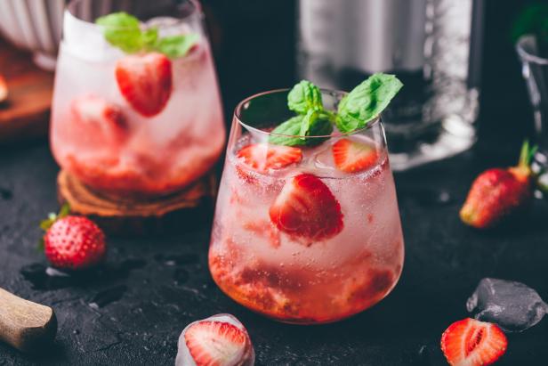 Ein erfrischender Cocktail mit Erdbeeren und Minze, serviert in einem Glas mit Eiswürfeln.