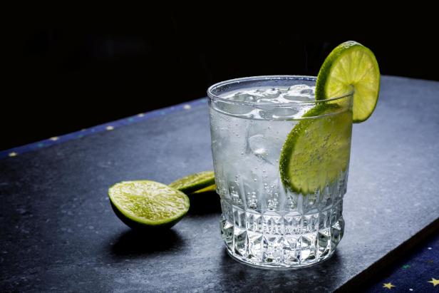 Ein Glas mit Wodka Soda und Limettenscheiben, garniert mit einer halben Limette.