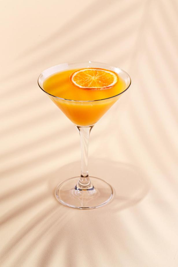 Ein Cocktail im Martiniglas ist mit einer Orangenscheibe garniert.