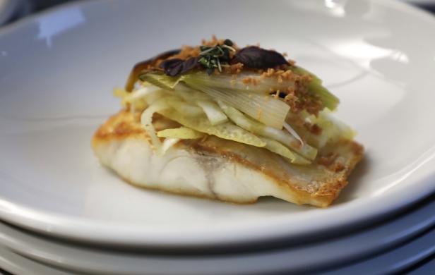 Ein Teller mit gebratenem Fisch, garniert mit Gemüse und Kräutern.