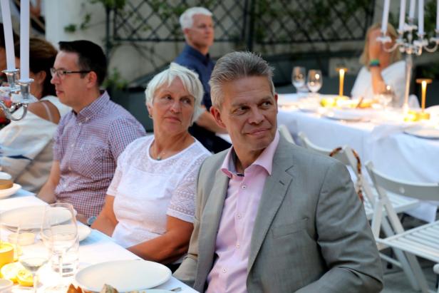 Gäste sitzen an einem festlich gedeckten Tisch im Freien.