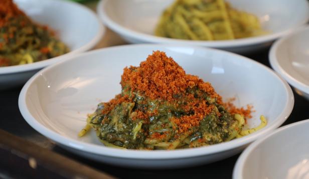 Ein Teller Pasta mit Spinat und gerösteten Semmelbröseln.