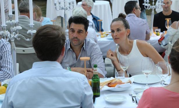 Gäste sitzen an einer festlich gedeckten Tafel bei einer Veranstaltung.