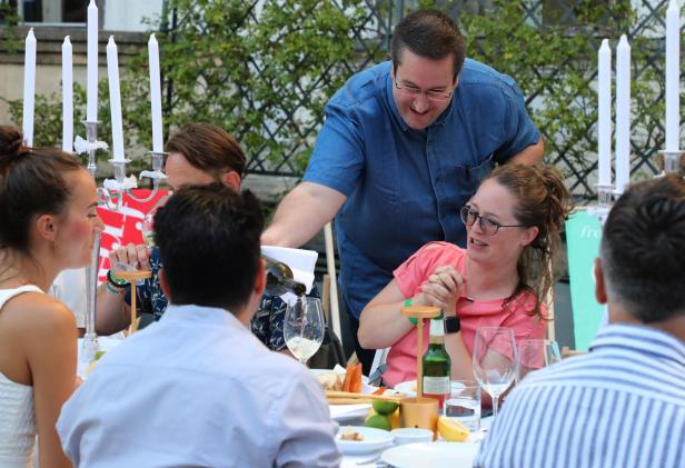 Ein Kellner schenkt Wein in ein Glas während einer Gartenparty ein.
