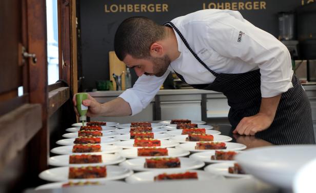 Ein Koch garniert Teller mit Speisen im Restaurant Lohberger.
