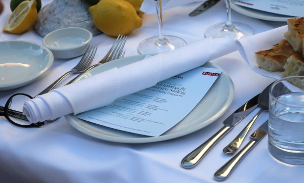 Ein gedeckter Tisch mit Zitronen, Tellern, Besteck und einer Speisekarte des Restaurants Pastamara.