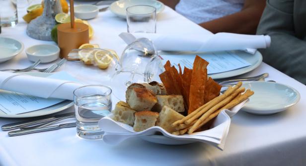 Ein gedeckter Tisch mit Brot, Grissini und Crackern in einem Korb.