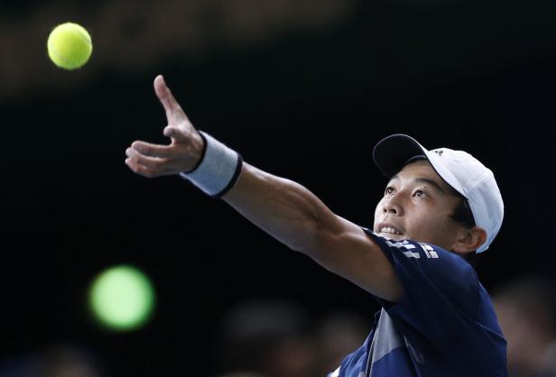 Ein Tennisspieler wirft einen Ball zum Aufschlag hoch.