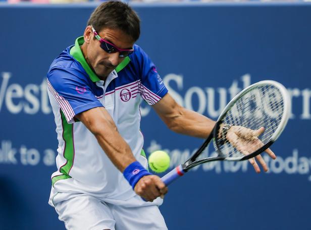 Ein Tennisspieler schlägt einen gelben Tennisball mit seinem Schläger.