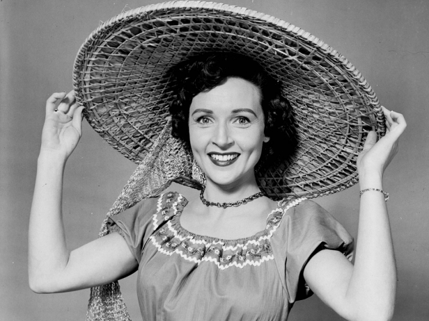 Betty White mit einem großen Strohhut lächelt in die Kamera.