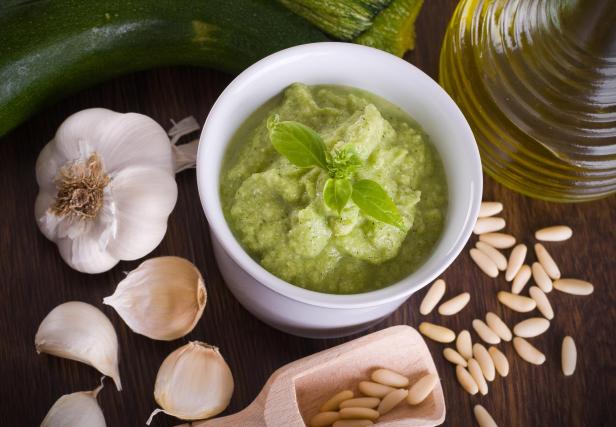 Zucchini-Pesto in einer weißen Schale mit Basilikum garniert.