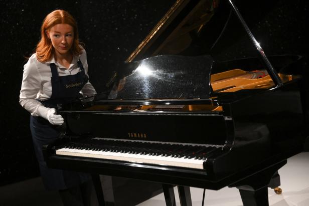 Eine Frau von Sotheby's steht neben einem schwarzen Yamaha-Flügel.
