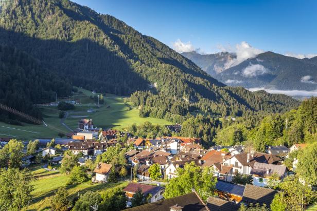 Ein Blick auf ein Dorf in einem Tal, umgeben von bewaldeten Bergen.