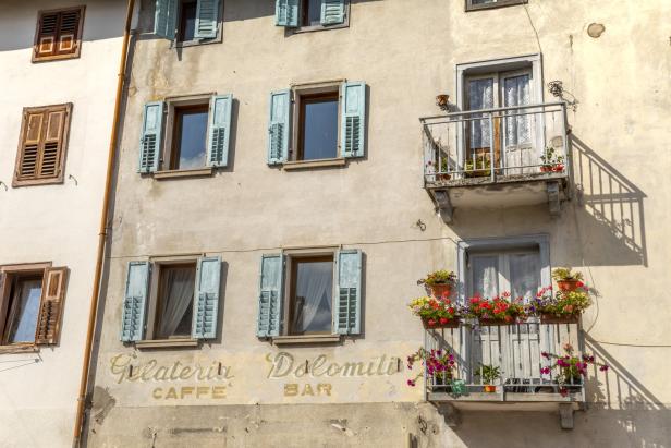 Die Fassade eines Gebäudes mit Fensterläden und Balkonen mit Blumenkästen.