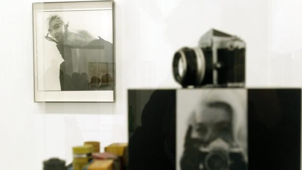 In einer Galerie sind Fotografien und eine Kamera ausgestellt.