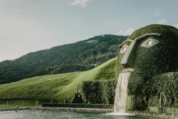 Ein grasbewachsenes Gesicht mit Wasserfall im Swarovski Kristallwelten Park.