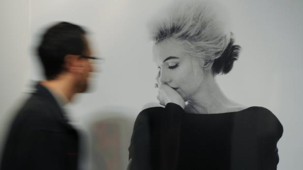Ein unscharfer Mann betrachtet ein Schwarz-Weiß-Porträt von Marilyn Monroe.
