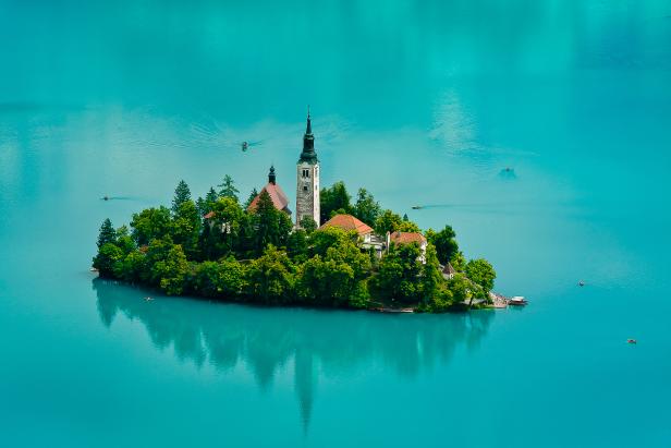 Eine Insel mit einer Kirche im türkisfarbenen Bleder See in Slowenien.