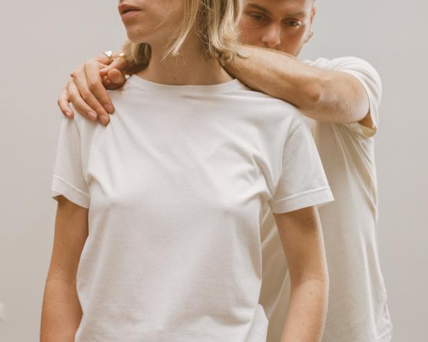 Ein Mann umarmt eine Frau, beide tragen weiße T-Shirts.