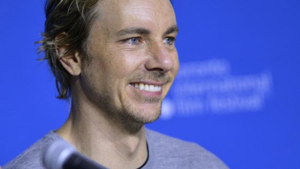 Dax Shepard lächelt vor einem blauen Hintergrund.