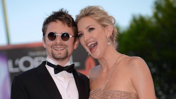 Kate Hudson und Matt Bellamy lächeln auf einem roten Teppich.
