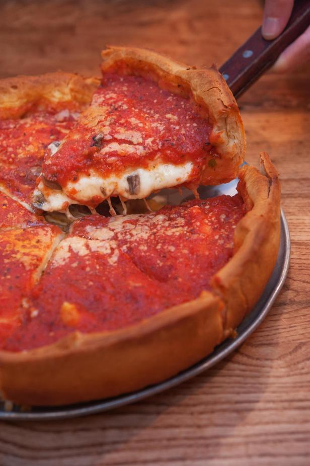 Eine Chicago Deep Dish Pizza wird auf einem Tisch serviert.