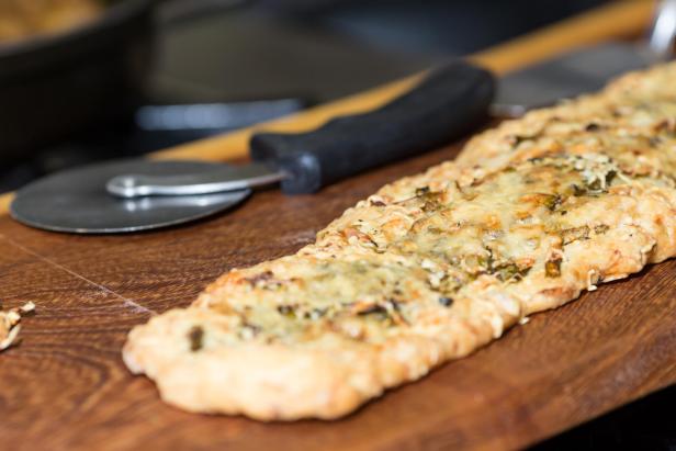 Eine „Coca zu Hause“ auf einem Holzbrett mit einem Pizzaschneider.