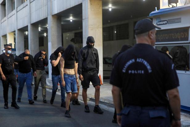 Police escort soccer fans to the police station in Athens