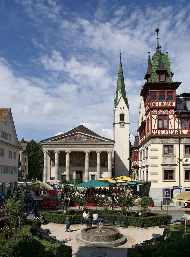 Blick auf den belebten Marktplatz von Bad Tölz mit Kirche und Brunnen.
