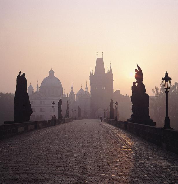 Die Karlsbrücke in Prag im Morgennebel mit ihren Statuen und dem Altstädter Brückenturm.