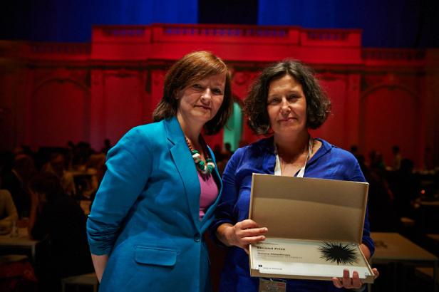 Zwei Frauen posieren mit einer Auszeichnung für „Second Prize: Stavros Niarchos Foundation“.